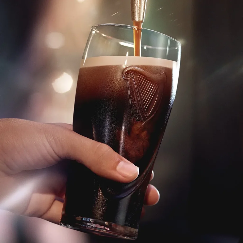 Pint of Guinness being poured into a branded glass
